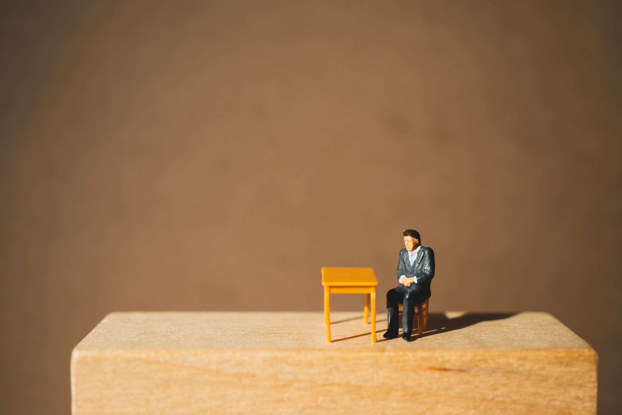 Miniature people, businessman sitting on wooden block using as b